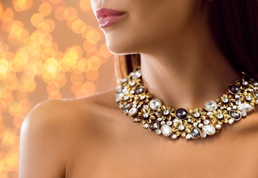 Photo of Beautiful young woman with elegant jewelry against defocused lights, closeup