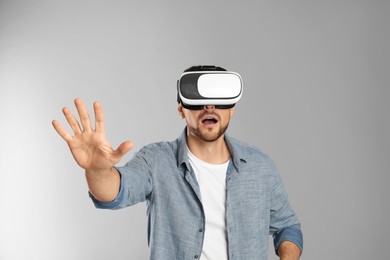 Photo of Man using virtual reality headset on grey background