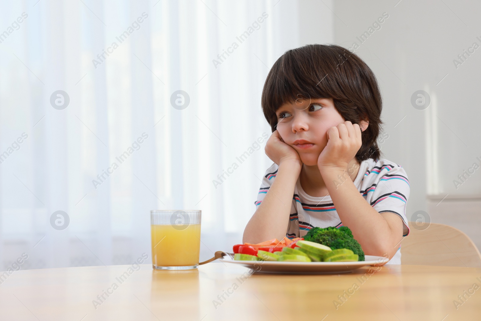 Photo of Cute little boy refusing to eat vegetables at home, space for text