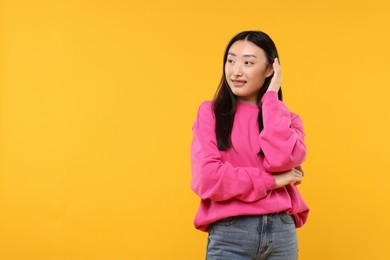 Photo of Portrait of smiling woman on orange background. Space for text