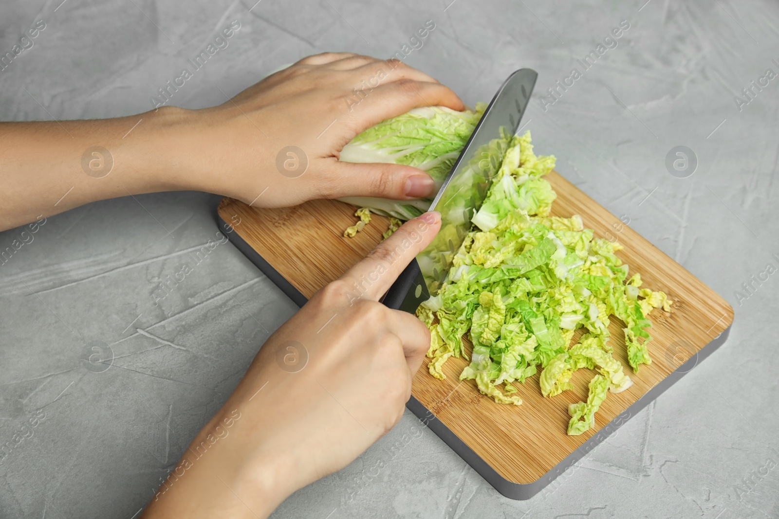 Photo of Woman cutting cabbage on wooden board