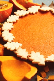 Pumpkins and delicious homemade pie on table, closeup