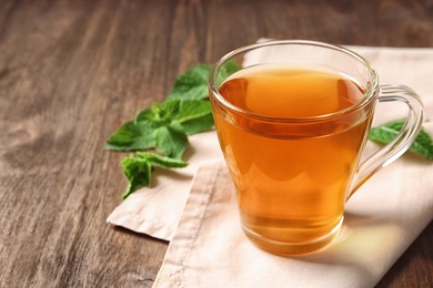 Photo of Cup with hot aromatic mint tea on wooden table
