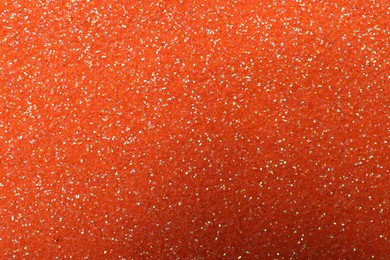 Photo of Beautiful shiny orange glitter as background, closeup