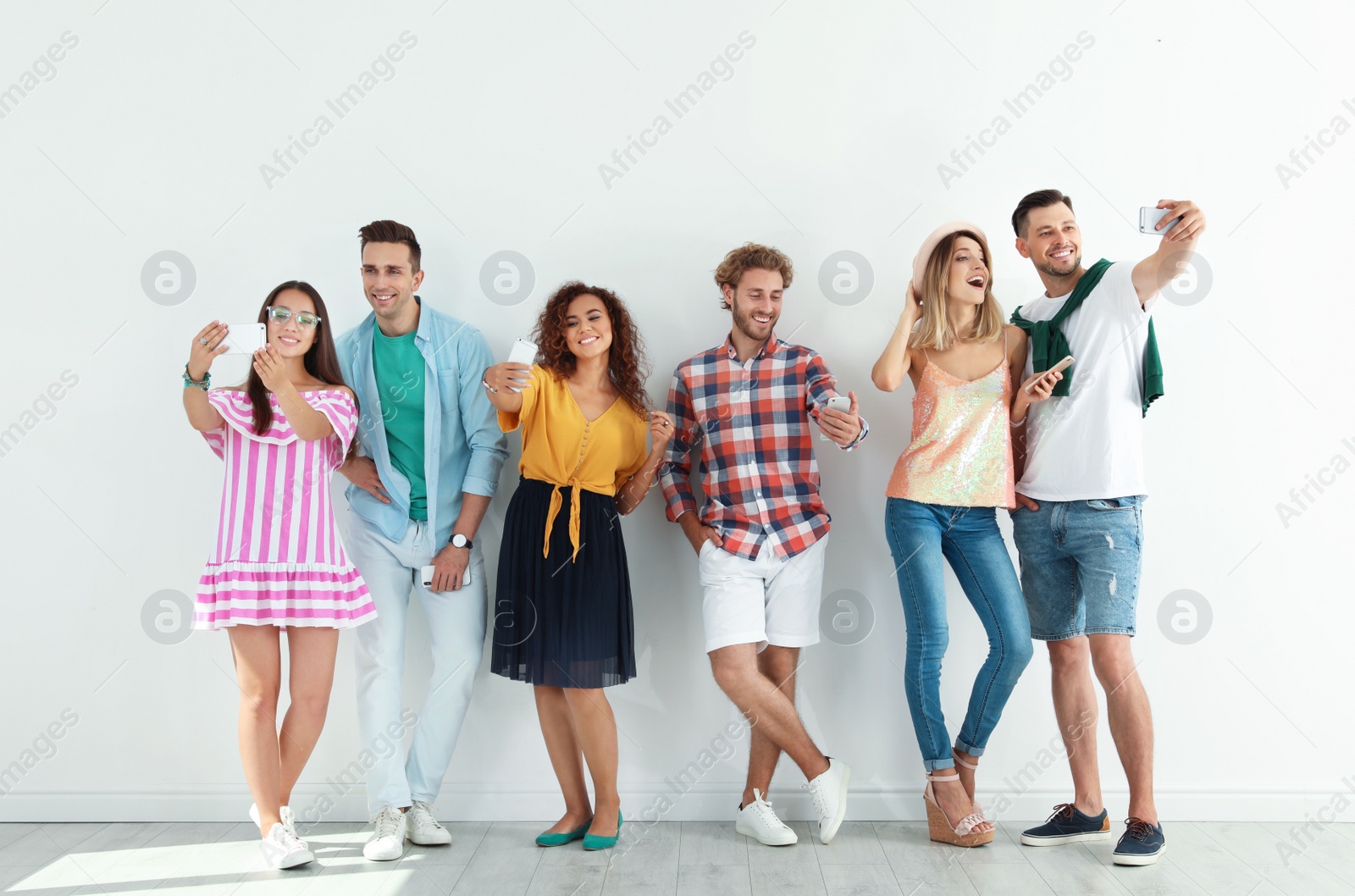 Photo of Group of young people taking selfie near white wall