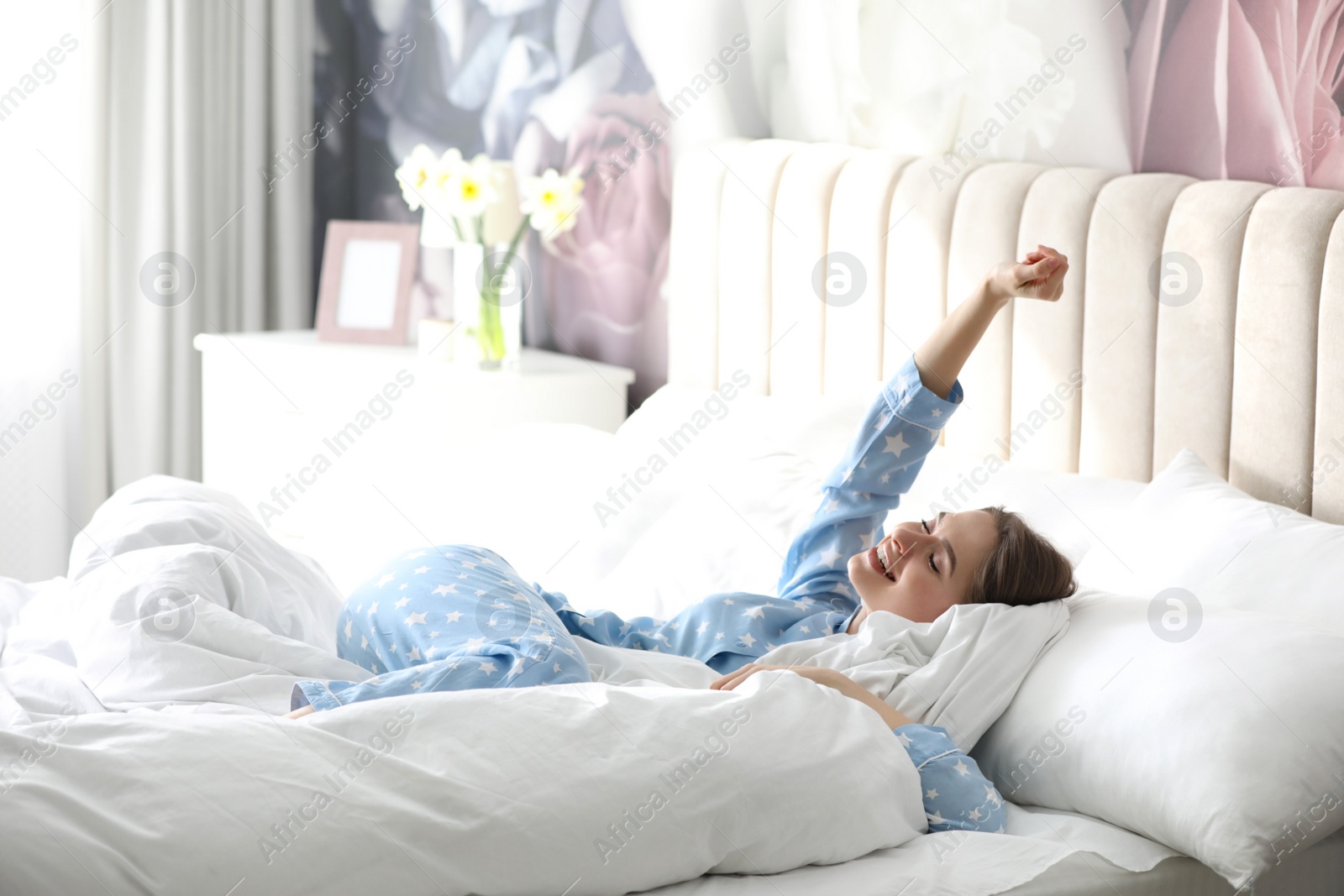 Photo of Young woman lying on comfortable pillow in bed at home