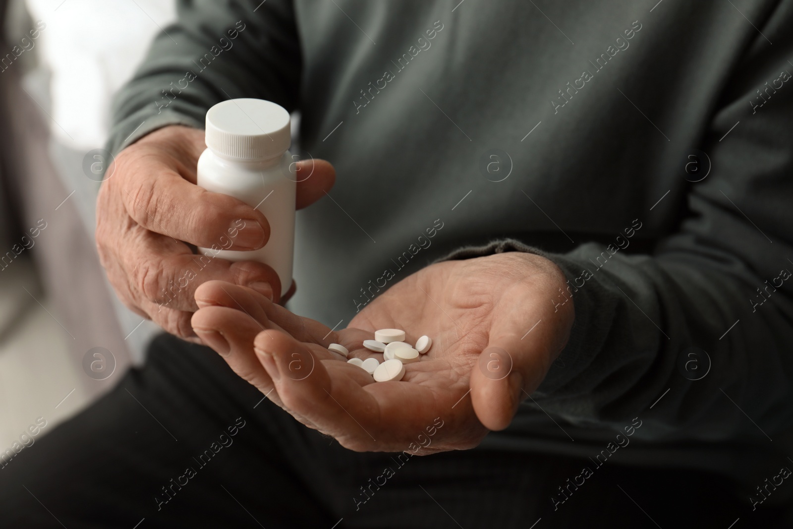 Photo of Senior man holding bottle and pills, closeup of hands