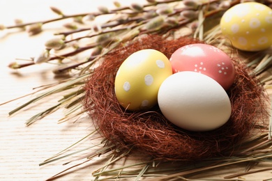 Photo of Sisal nest with painted Easter eggs on wooden table. Space for text