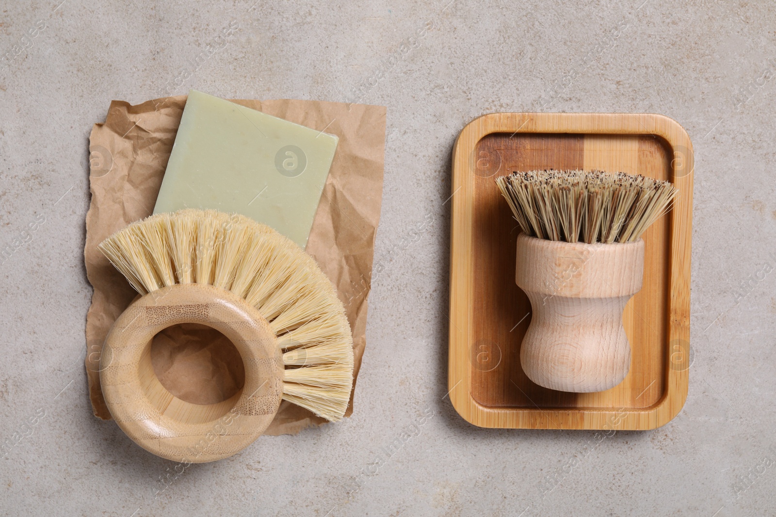 Photo of Cleaning brushes and soap bar on light grey table, top view