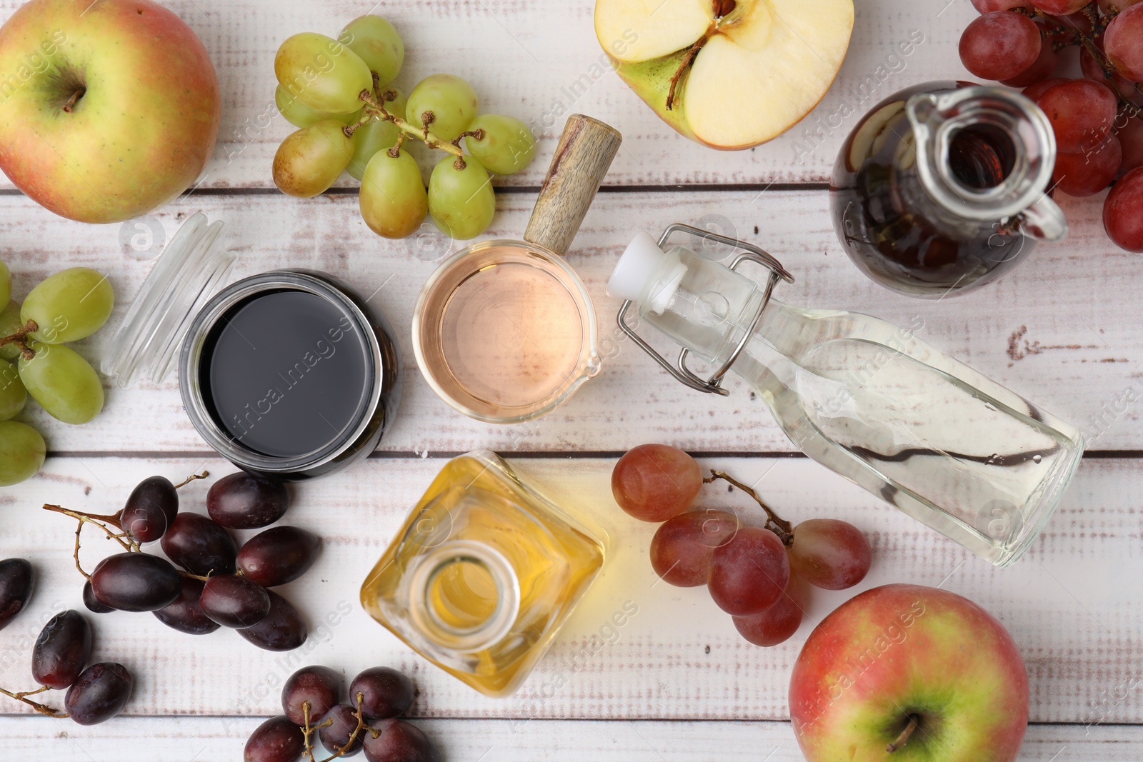 Photo of Different types of vinegar and ingredients on wooden table, flat lay