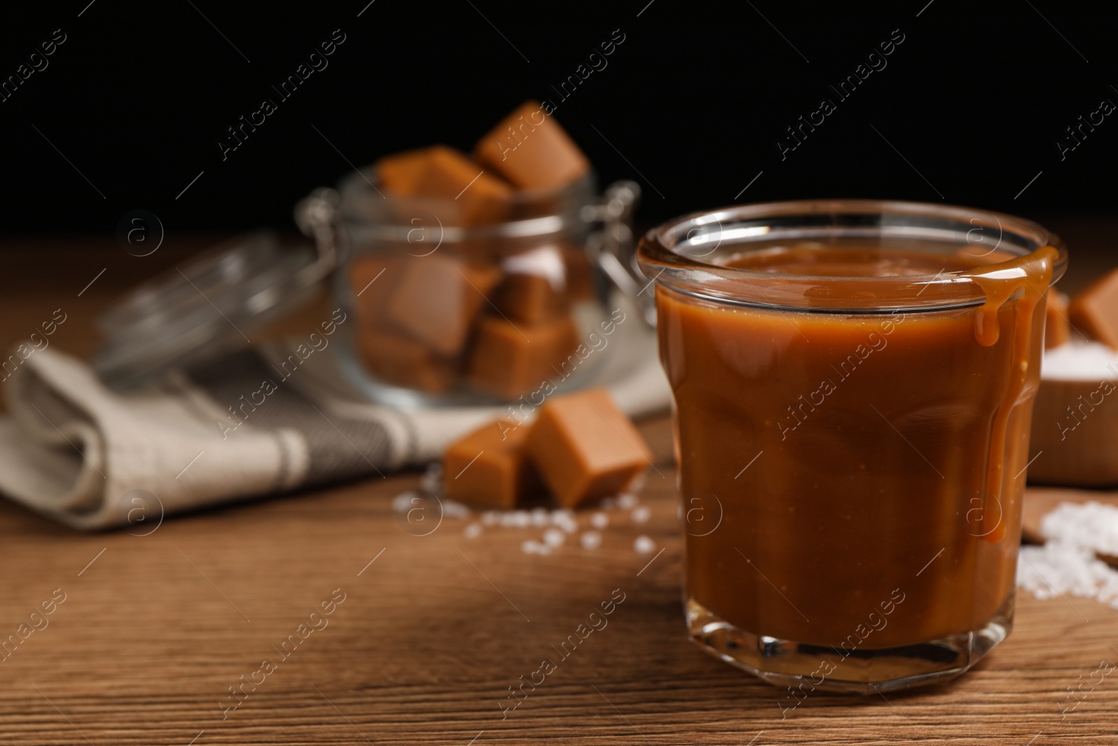 Photo of Tasty salted caramel on wooden table, space for text