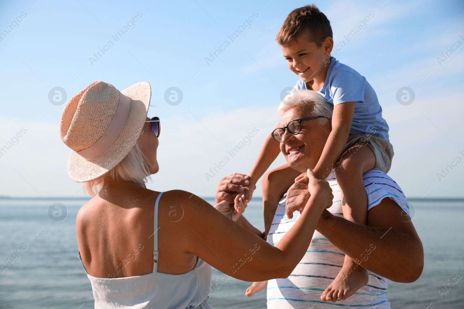 Photo of Cute little boy with grandparents spending time together near sea