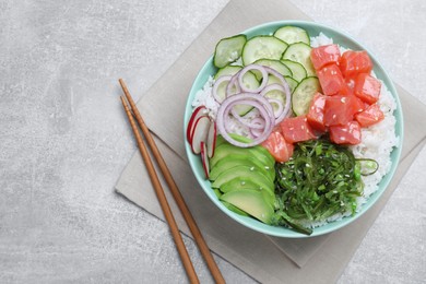 Photo of Delicious poke bowl with salmon, seaweed and vegetables served on light grey table, flat lay