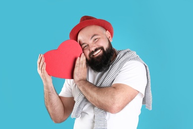 Emotional man with heart shaped box on color background