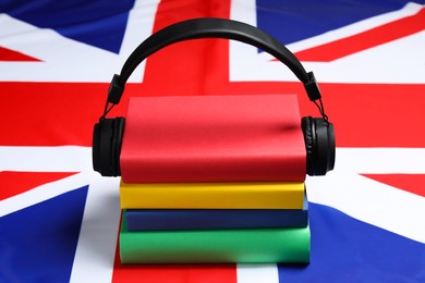 Photo of Learning foreign language. Different books and headphones on flag of United Kingdom