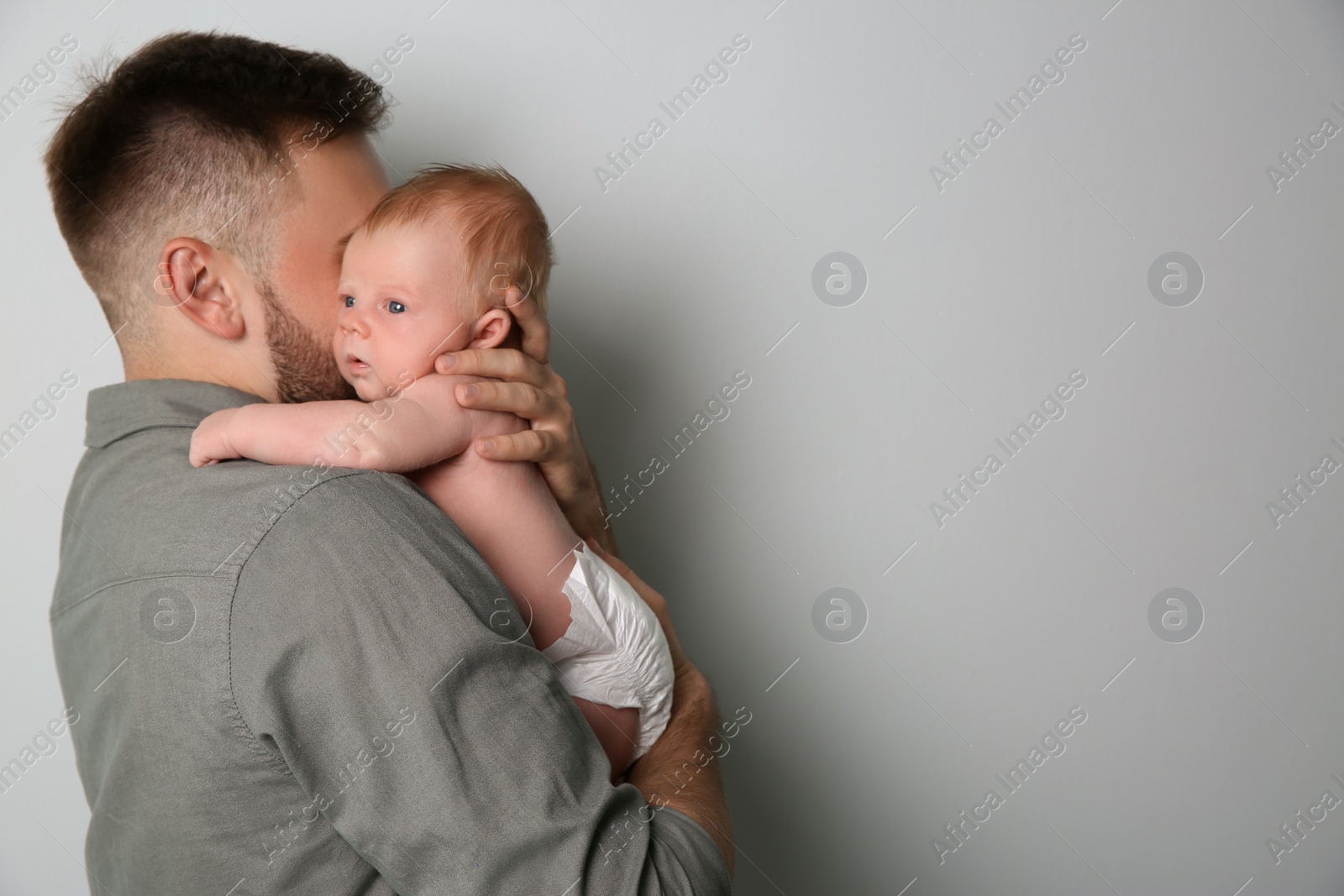 Photo of Father with his newborn son on light grey background. Space for text