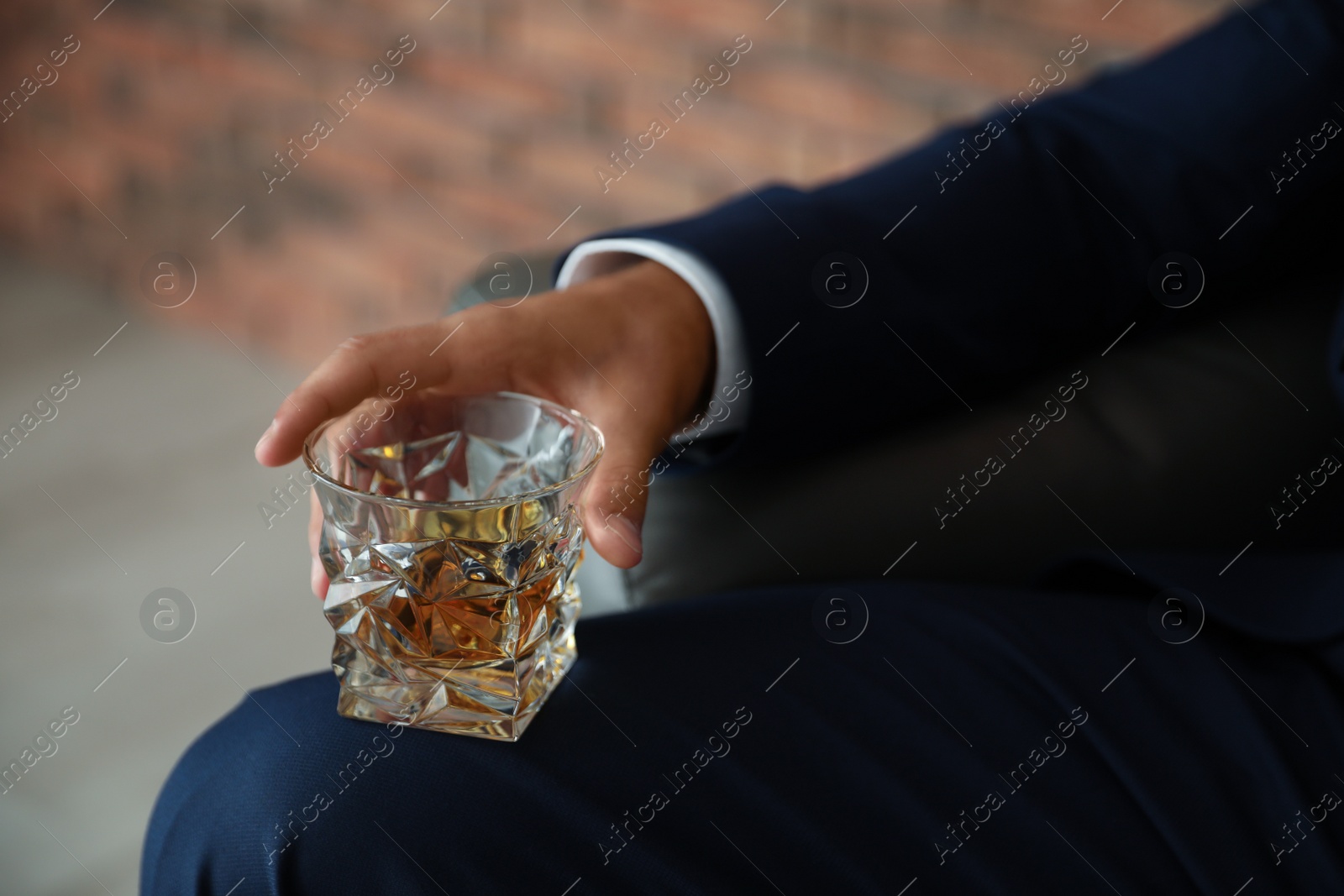Photo of Young man with glass of whiskey indoors, closeup