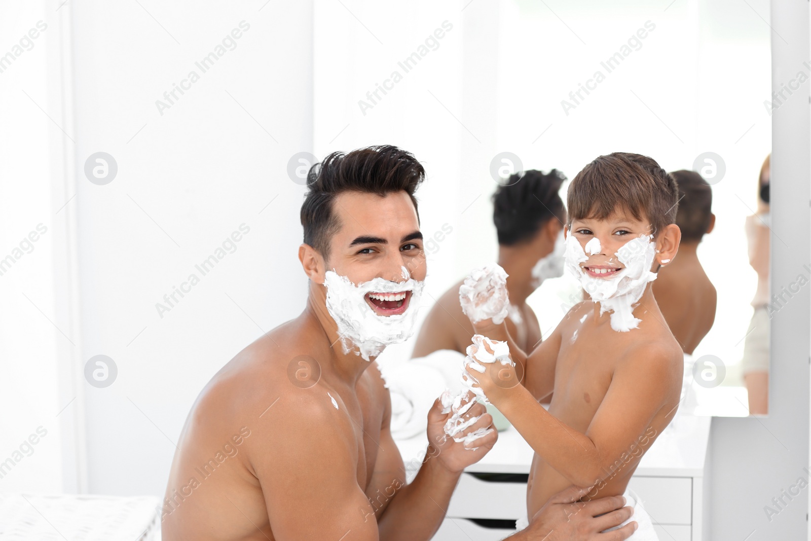 Photo of Father and son having fun while applying shaving foam in bathroom