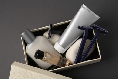 Different men's shaving accessories and box on dark grey background, top view