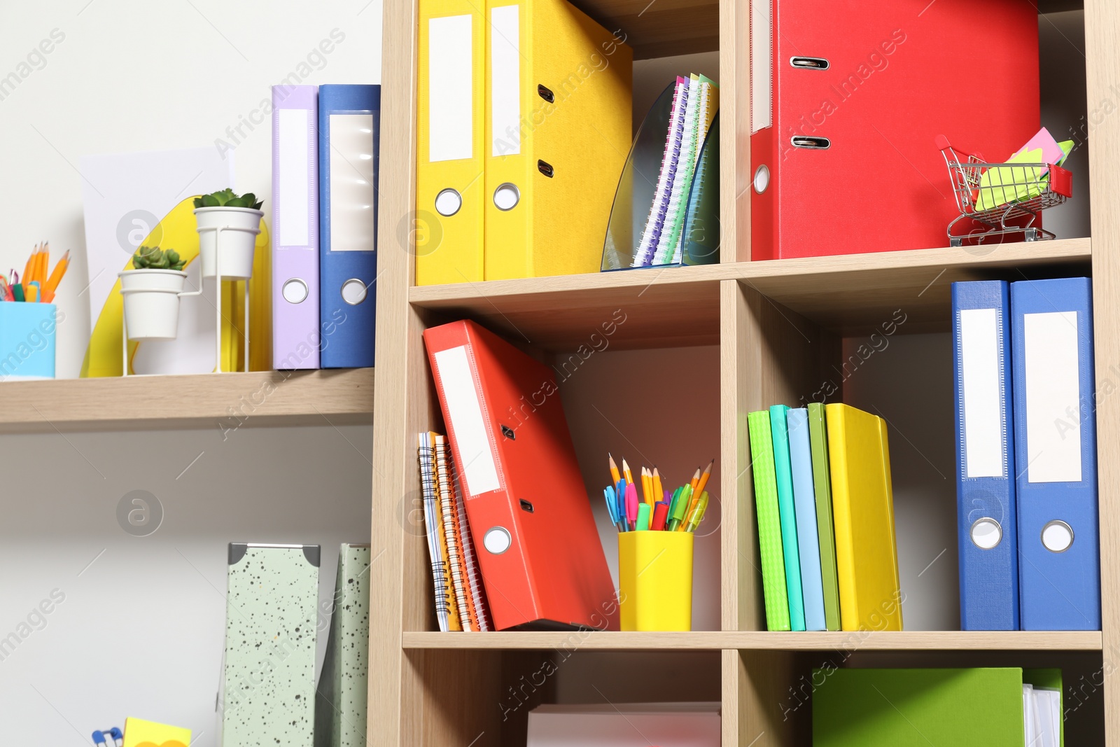 Photo of Colorful binder office folders and other stationery on shelving unit indoors