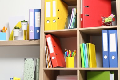 Photo of Colorful binder office folders and other stationery on shelving unit indoors