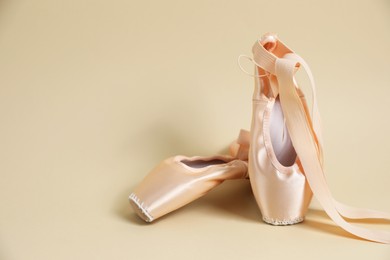 Photo of Ballet shoes. Elegant pointes on beige background. Space for text