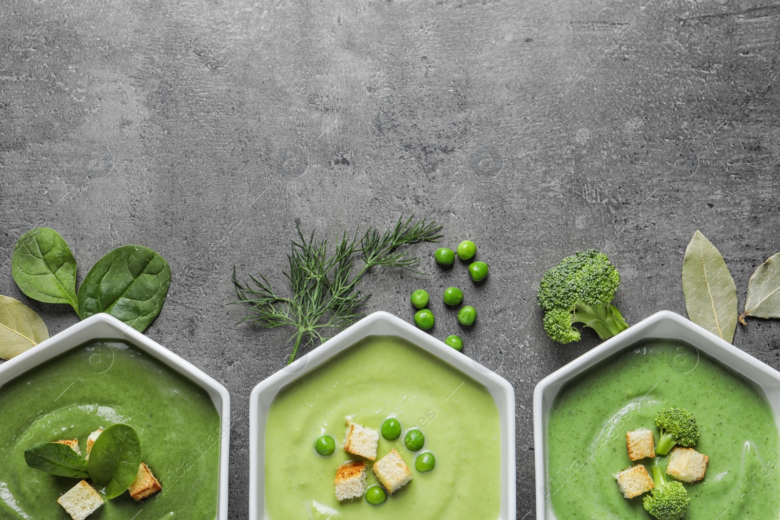 Photo of Flat lay composition with different fresh vegetable detox soups made of green peas, broccoli and spinach in dishes on table. Space for text