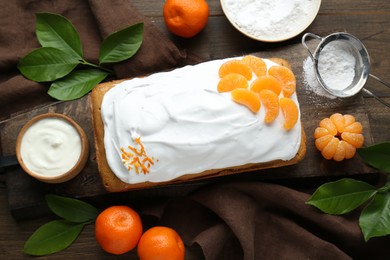 Photo of Delicious homemade yogurt cake with tangerines and cream on wooden table, flat lay