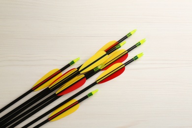 Plastic arrows on white wooden table, flat lay. Archery sports equipment