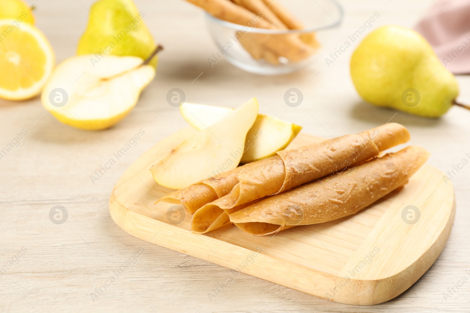 Photo of Delicious fruit leather rolls and pears on white wooden table. Space for text