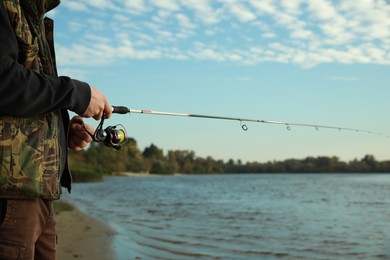 Fisherman with rod fishing at riverside, closeup