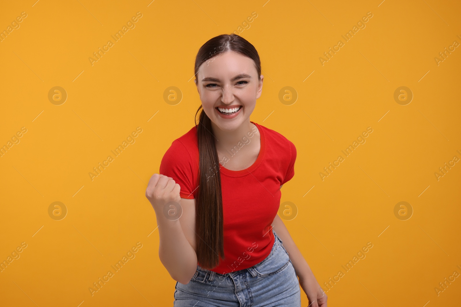 Photo of Happy sports fan celebrating on orange background