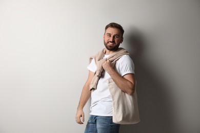 Happy man with eco bag on light background. Space for text