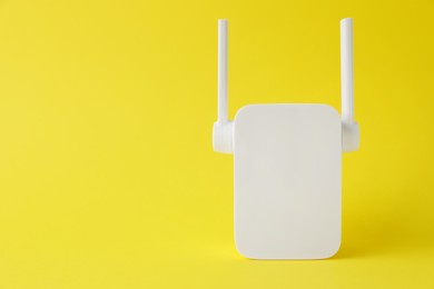 Photo of New modern Wi-Fi repeater on yellow background, space for text