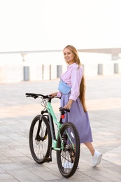 Photo of Young woman with bicycle in city on sunny day