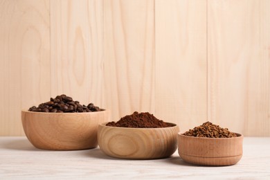 Photo of Bowls with different types of coffee on white wooden table