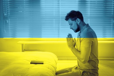 Pray for Ukraine. Double exposure of man with Bible praying in room and Ukrainian national flag