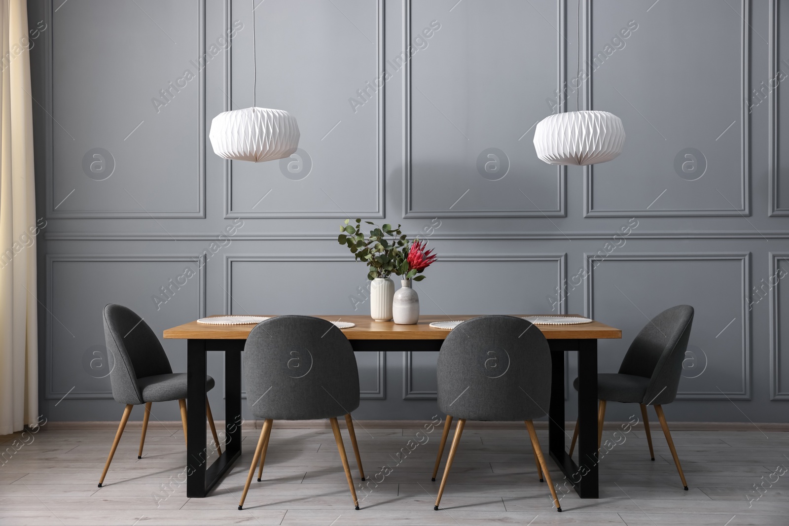 Photo of Soft chairs, table and vases with plants in stylish dining room