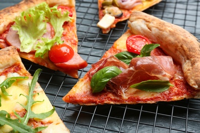 Photo of Slices of different delicious pizzas on grey wooden table, closeup