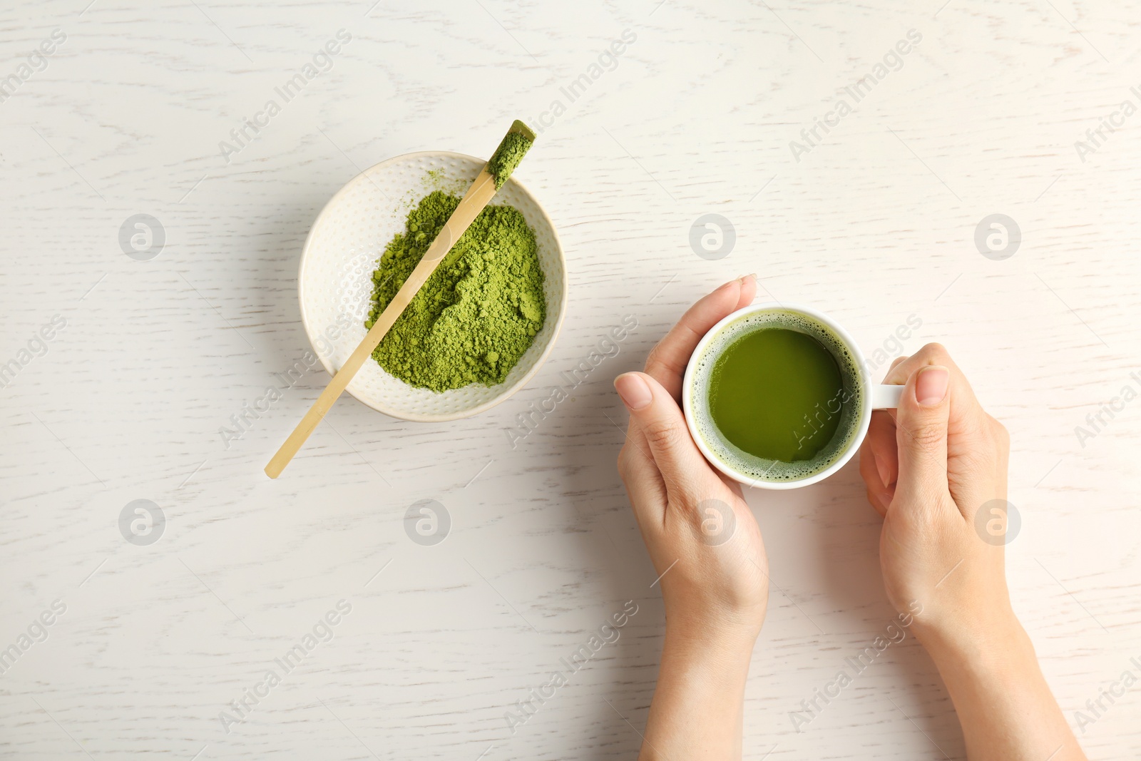 Photo of Woman with cup of matcha tea at table, top view