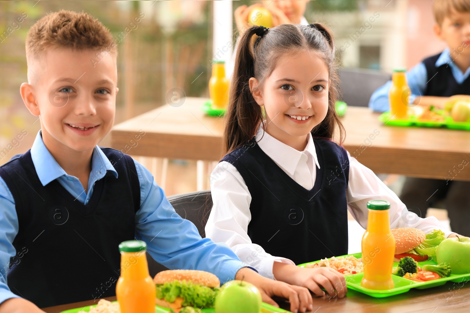 Photo of Happy children at table with healthy food in school canteen