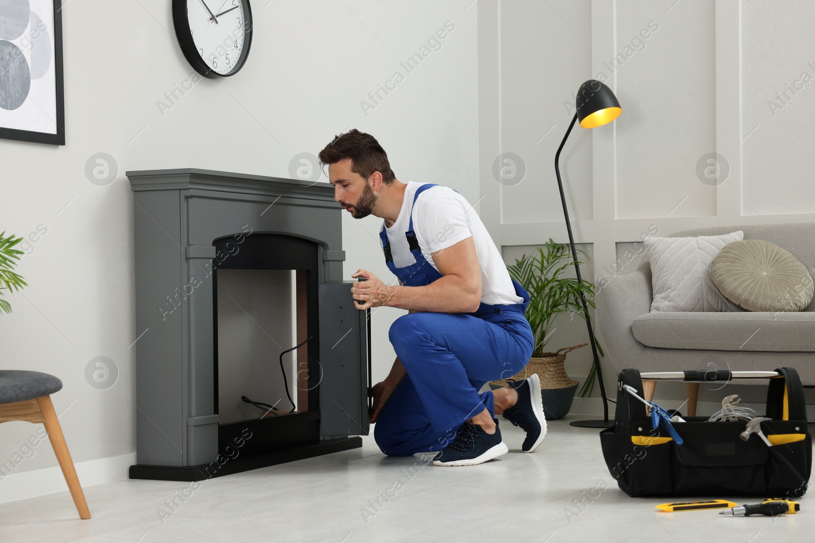 Photo of Professional technician installing electric fireplace in room