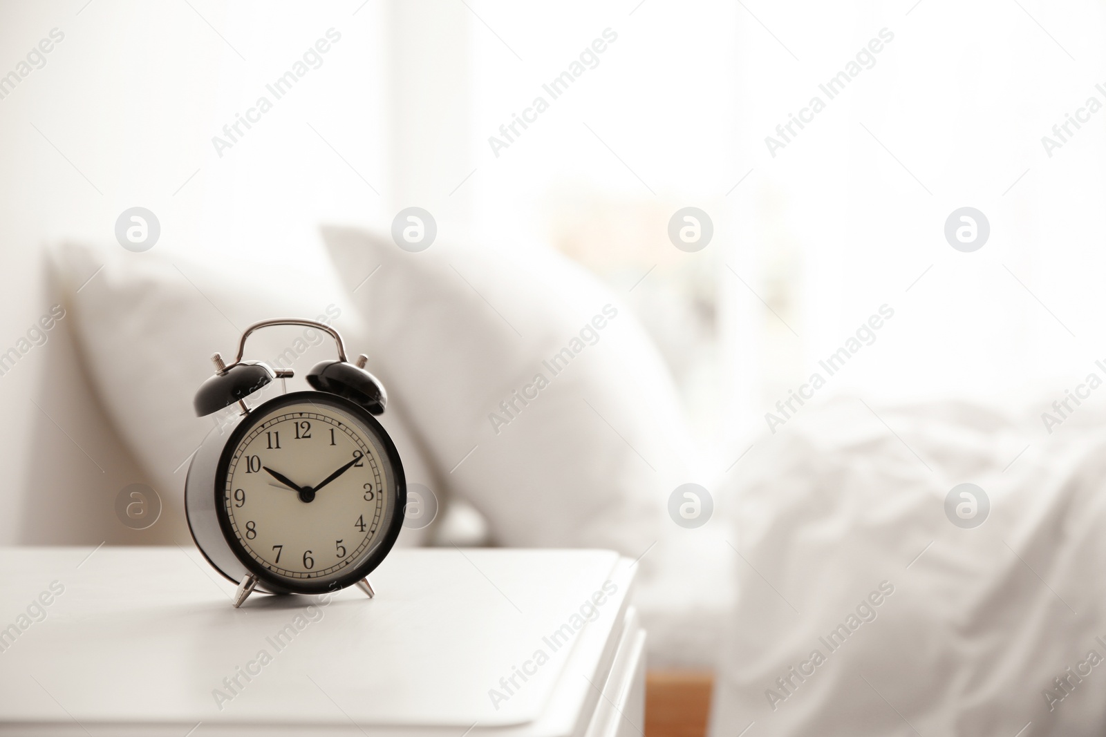 Photo of Black alarm clock on nightstand in morning. Space for text