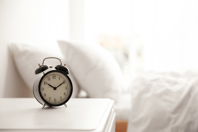 Photo of Black alarm clock on nightstand in morning. Space for text