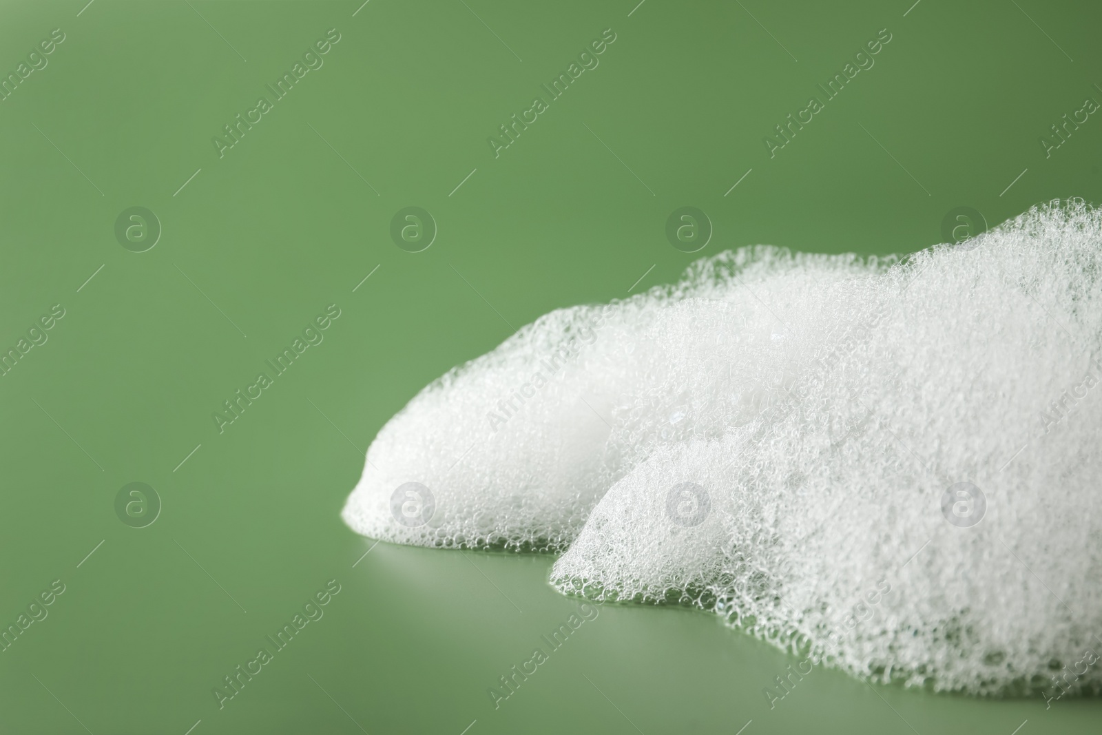 Photo of Fluffy bath foam on olive background, closeup. Space for text