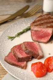 Photo of Delicious grilled beef steak with tomatoes on table, closeup