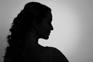 Silhouette of one woman on light grey background, profile portrait. Space for text