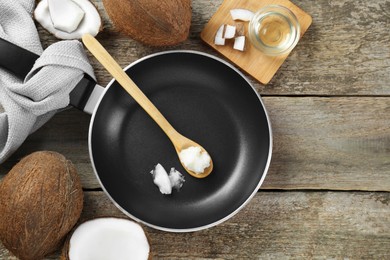 Photo of Flat lay composition with frying pan and organic coconut cooking oil on wooden table, space for text