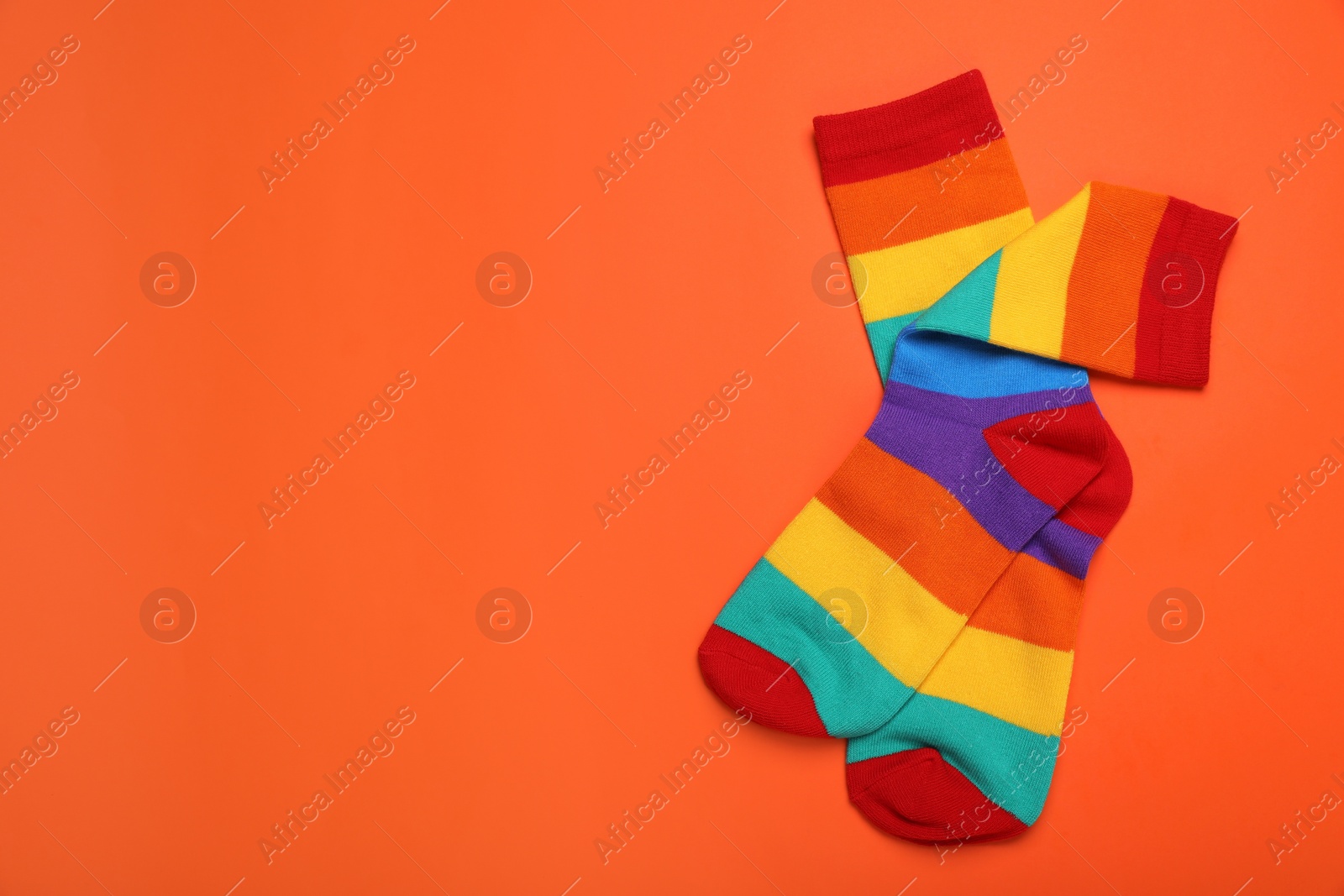 Photo of Rainbow socks on orange background, flat lay with space for text. LGBT pride