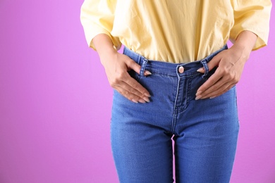 Woman in stylish blue jeans on color background